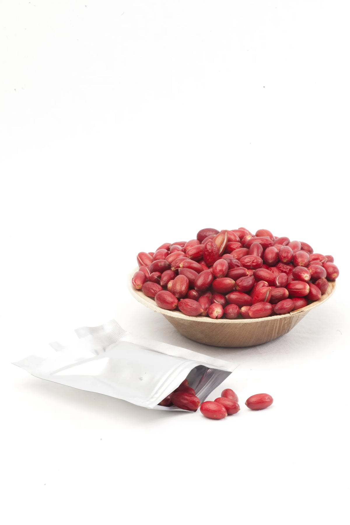 A bowl of fresh red miracle berries next to a silver Zafru brand freshness packet on a white background.