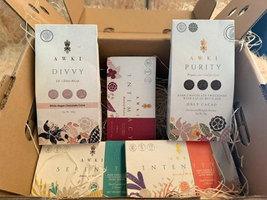 A curated gift box of AWKI chocolates including Divvy White Vegan Coins, Purity Dark Chocolate with Mucilage, and Intimacy 75% Arriba bars.