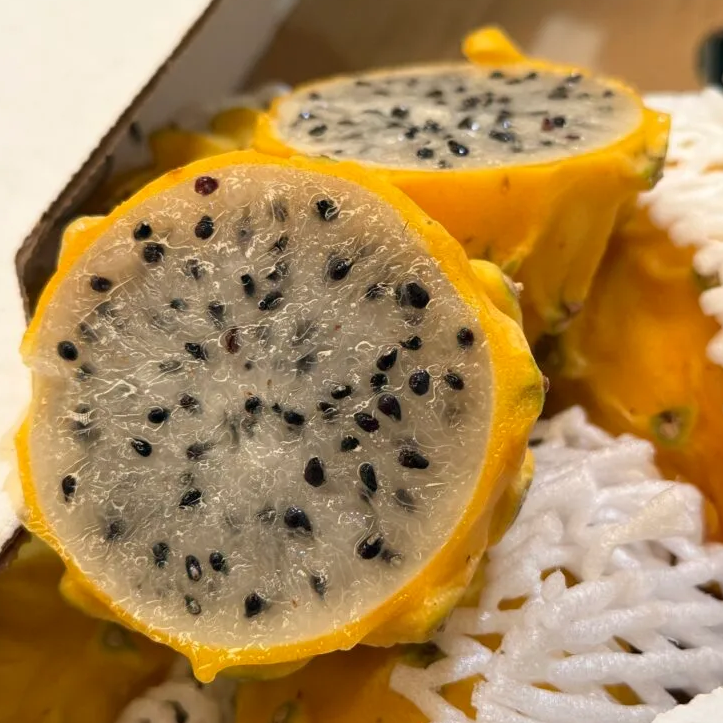 Close-up of sliced yellow dragon fruit on a textured surface