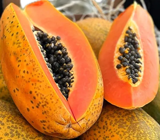 Close-up of fresh organic bio papayas sliced open to reveal vibrant orange flesh and a center of black edible seeds.