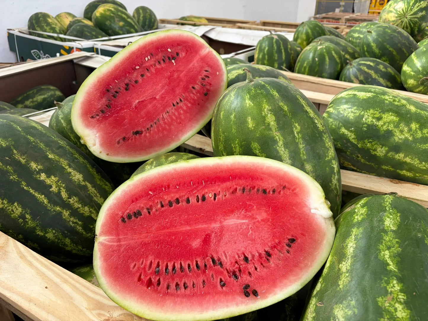 Watermelons with a focus on halved watermelon showing red flesh and green rind.