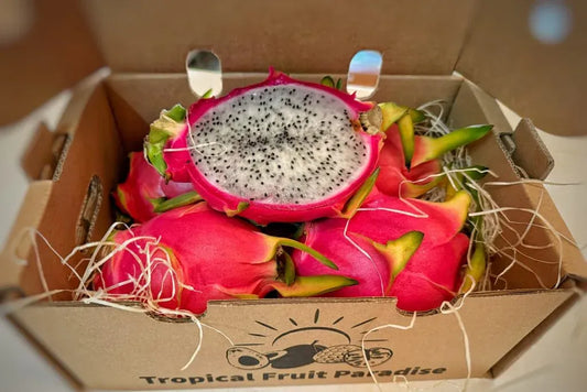 Fresh white dragon fruit (pitaya blanca) sliced in half to show the crisp white flesh with tiny black seeds and vibrant pink skin.