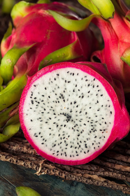 A close-up of a fresh white dragon fruit (pitaya blanca) from Ecuador, sliced in half to show the crisp white flesh with tiny black seeds and vibrant pink skin.